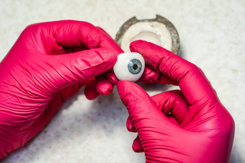 Gloved hands holding an artificial eye