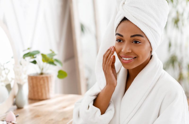 Woman in robe touching her face and smiling